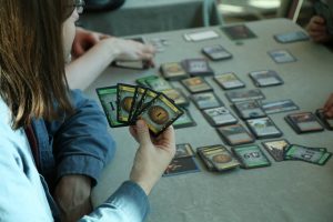 A person with a hand of cards to the camera playing the game Dominion