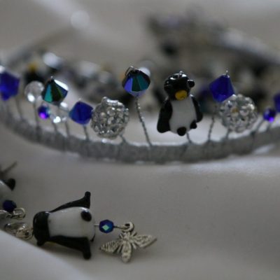 A closeup of a tiara with blue beads and penguin charms