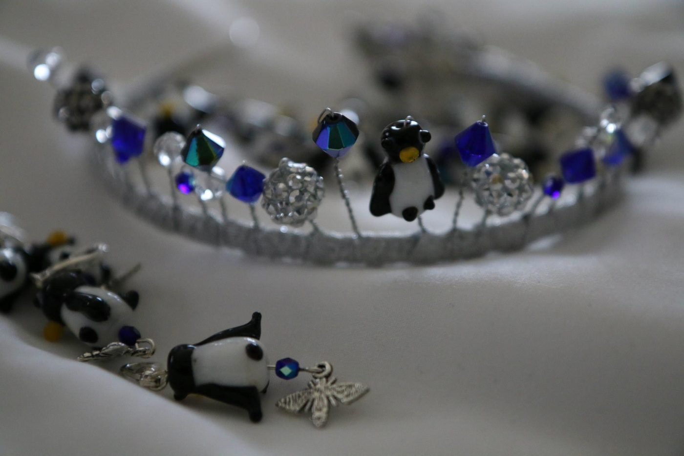 A closeup of a tiara with blue beads and penguin charms