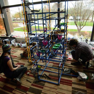 Giant marble machine being worked on by four people